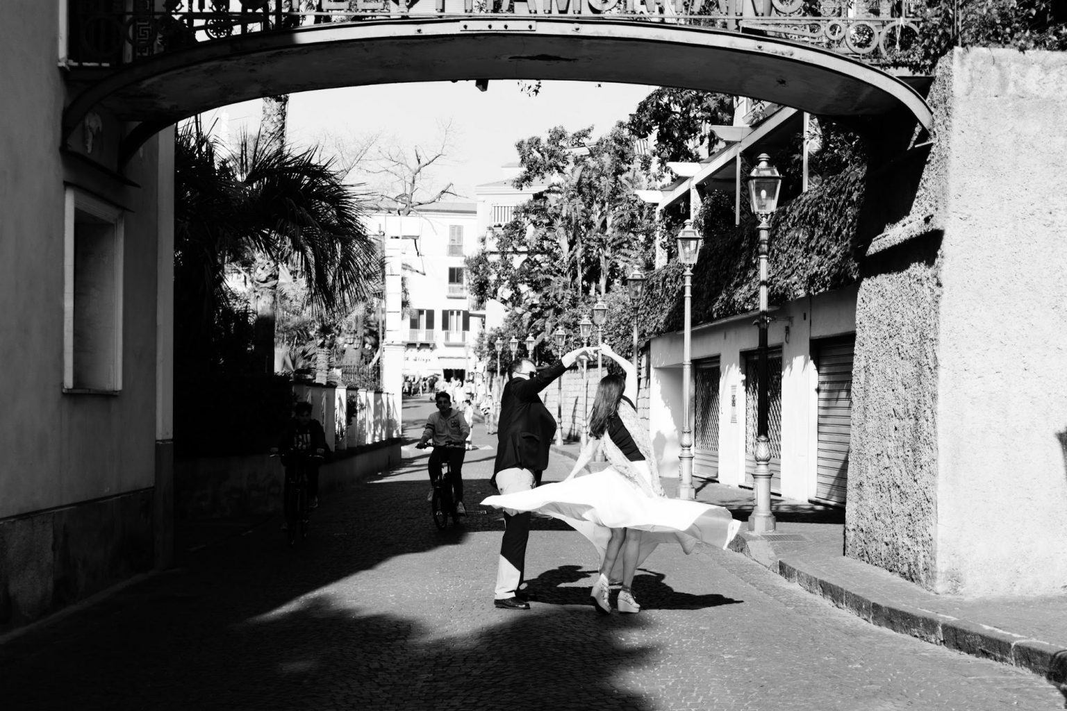 A black and white wedding photo of a bride and groom walking down a street.