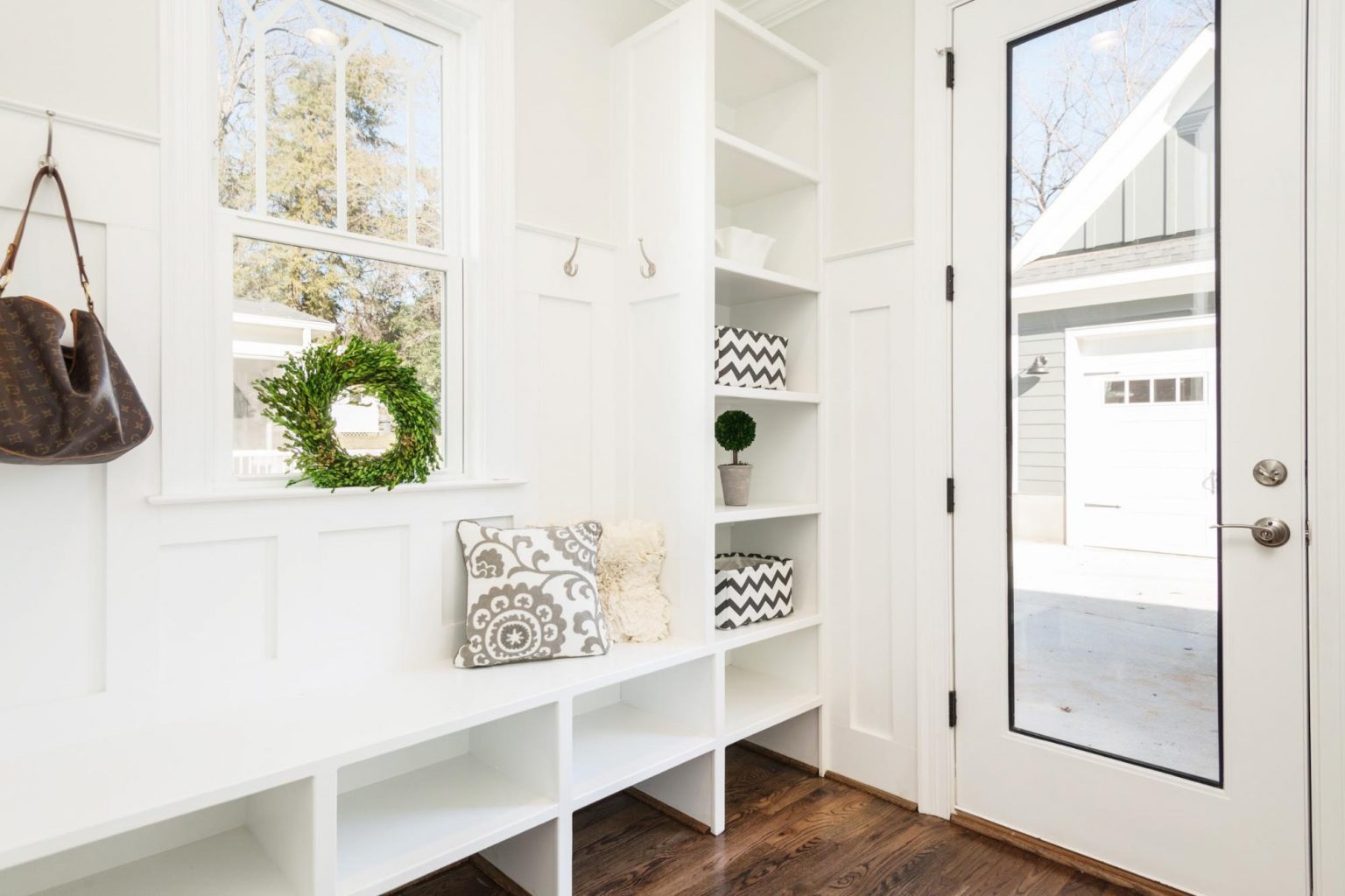 A white entryway with a bench and bookshelves, perfect for a wedding or special occasion.