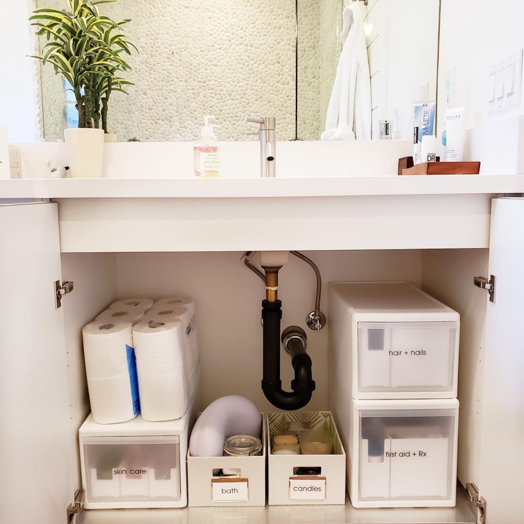 An organized bathroom with a sink and toilet paper dispenser.