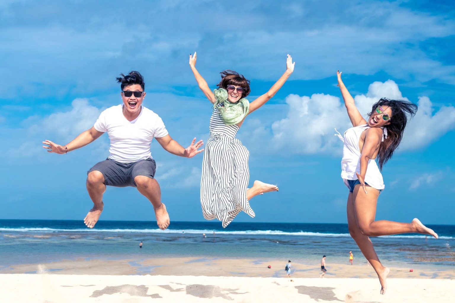 An organized group of people jumping in the air on a beach.