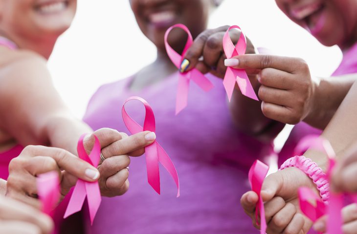 A group of women holding pink ribbons in support of breast cancer prevention.