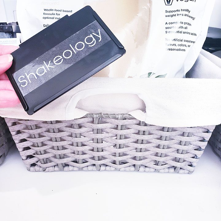 A person holding a basket with shakeology products in it.