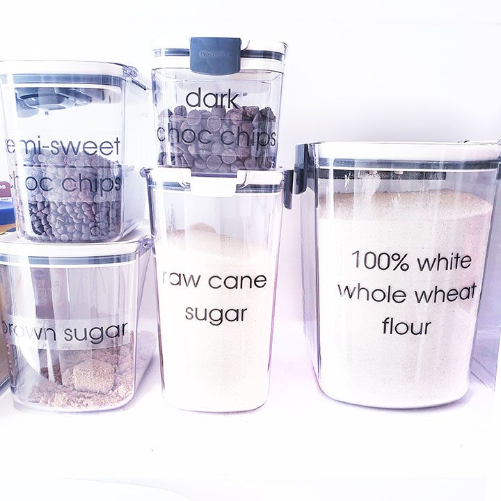 A variety of containers with different types of flour and sugar.