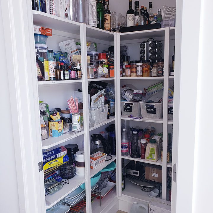 A white pantry with a lot of items in it.