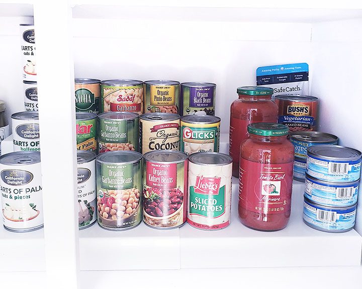 Canned food in a white kitchen cabinet.