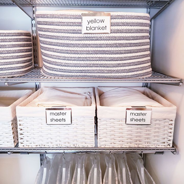 An organized laundry room with labeled baskets on the shelves, perfect for helping you organize your linen closet.