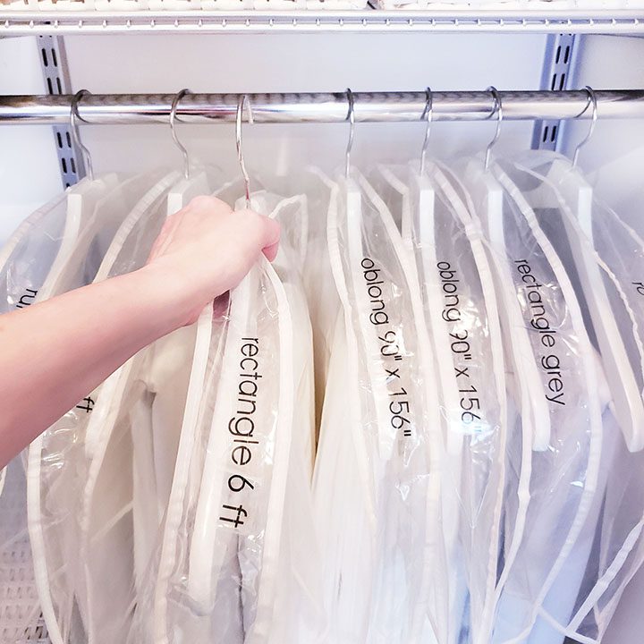 A person is organizing their linen closet by putting clothes on hangers.