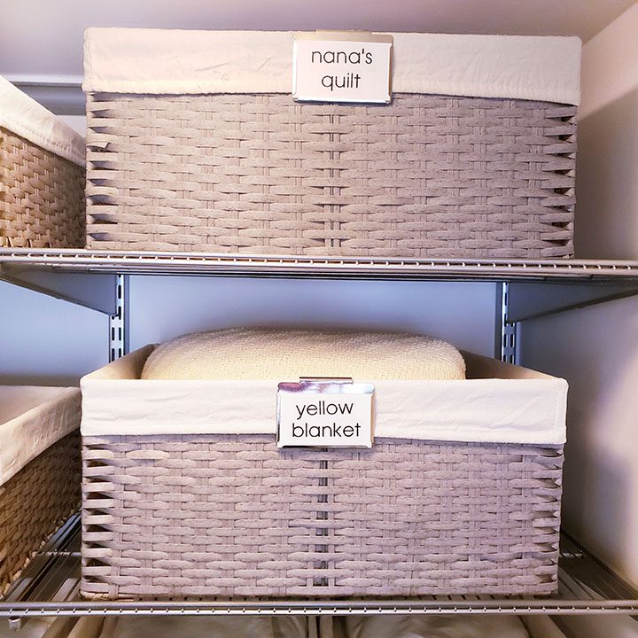 A closet full of wicker baskets with labels on them to help organize your linen closet.
