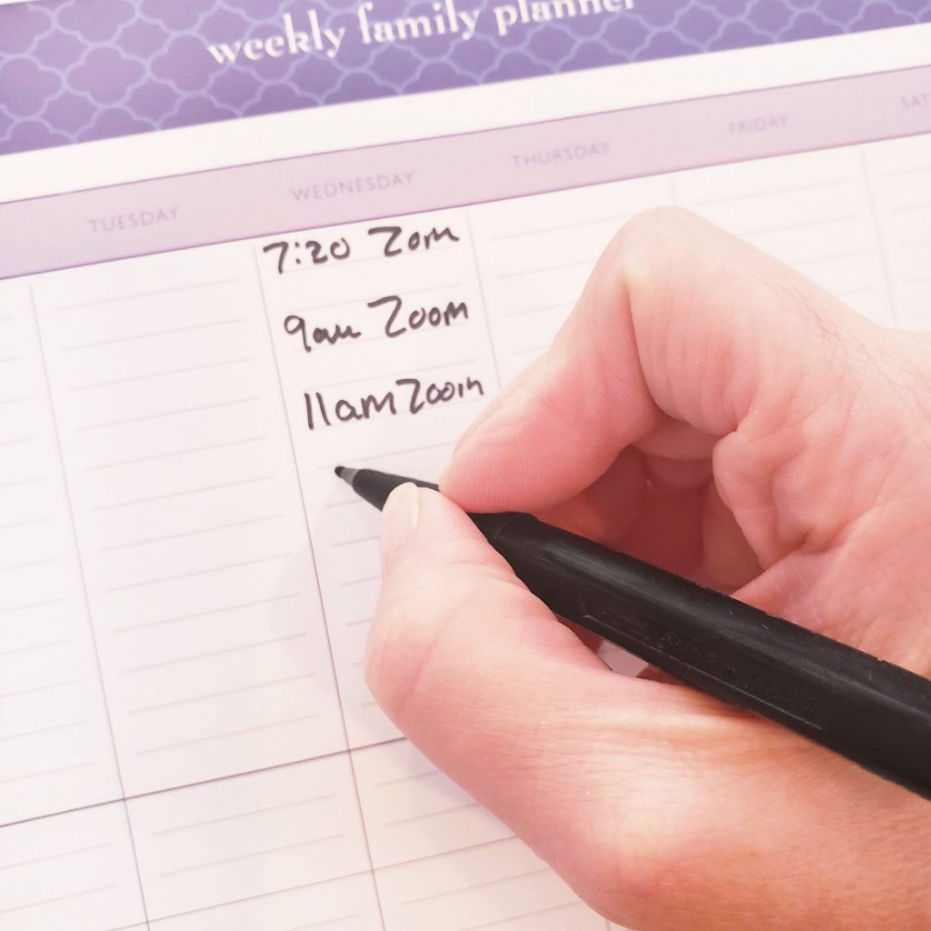 A person using a weekly family planner to organize their schedule.