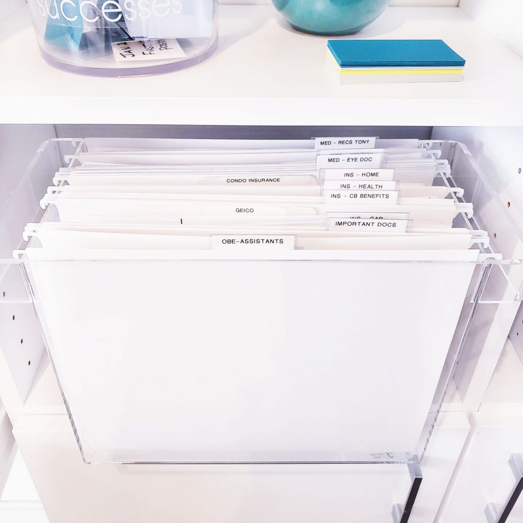 A white file cabinet filled with a multitude of organized papers.