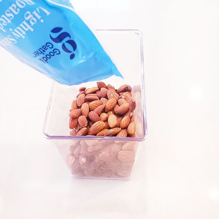 Almonds in a plastic container inside a pantry.