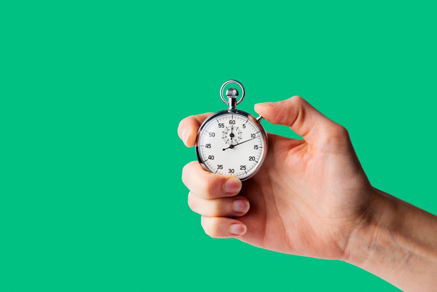 A hand holding a stopwatch, measuring habits, on a green background.
