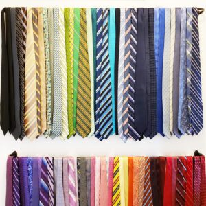 Many different colored valentine ties hanging on a wall.