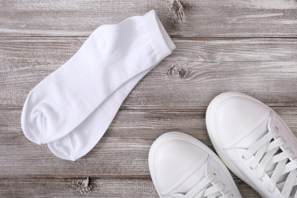 A pair of white sneakers and white socks on a wooden background, perfect for Spring Break.