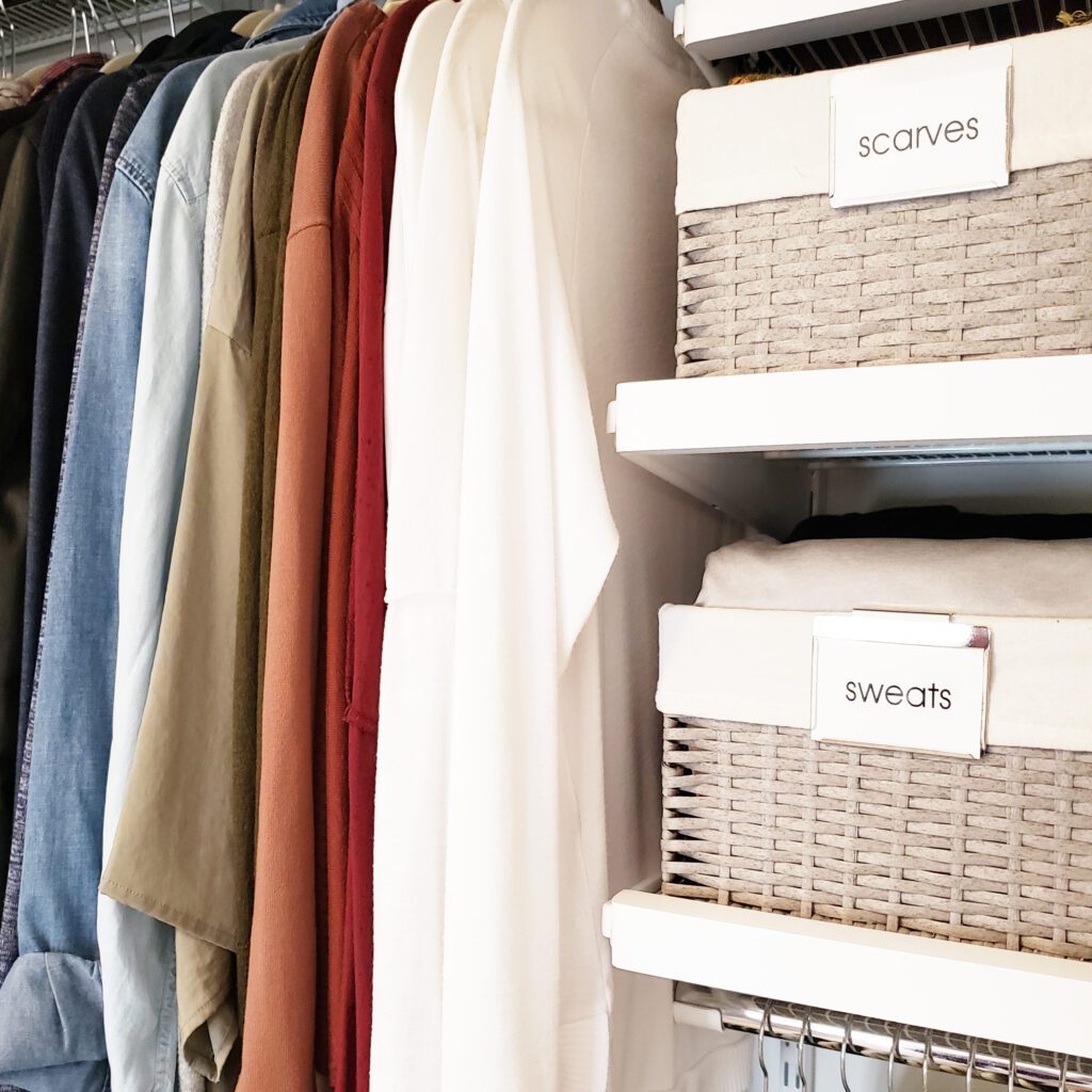 A closet full of summer clothes and wicker baskets.