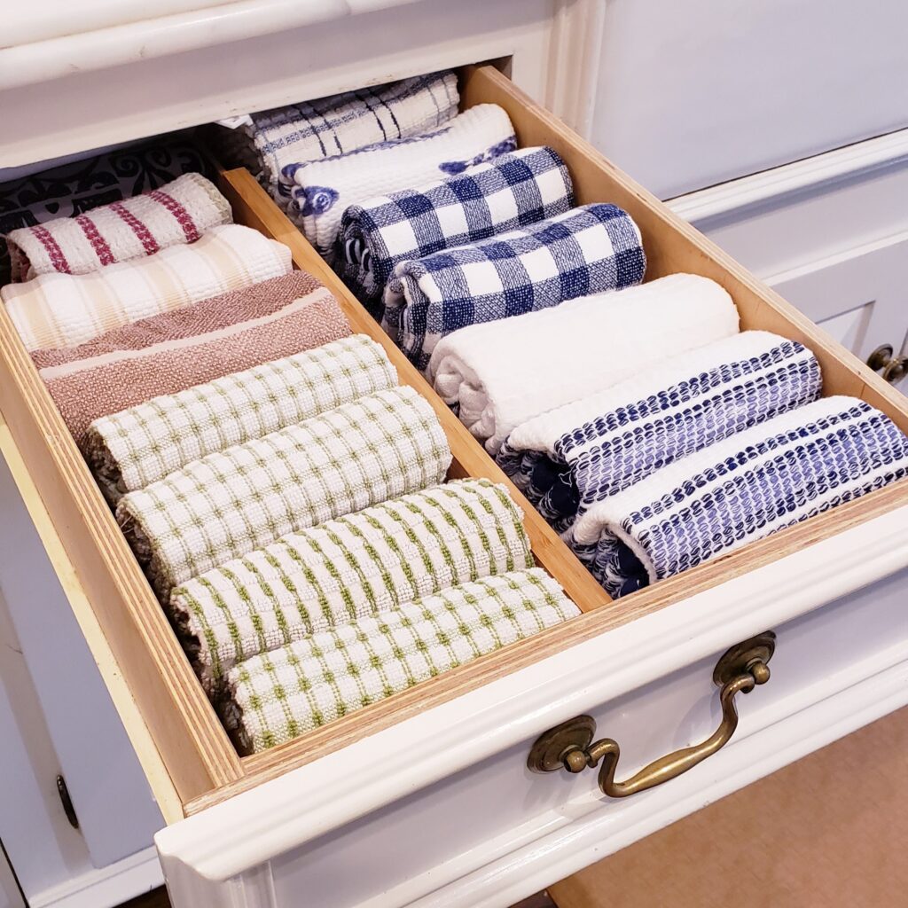 A drawer full of towels in a white cabinet with drawers.