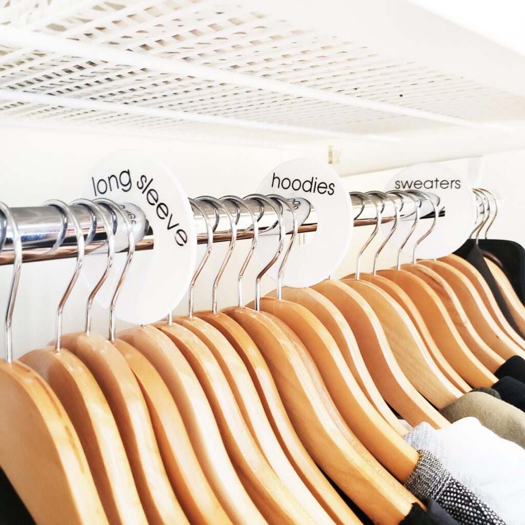 A summer closet full of clothes and hangers with labels on them.