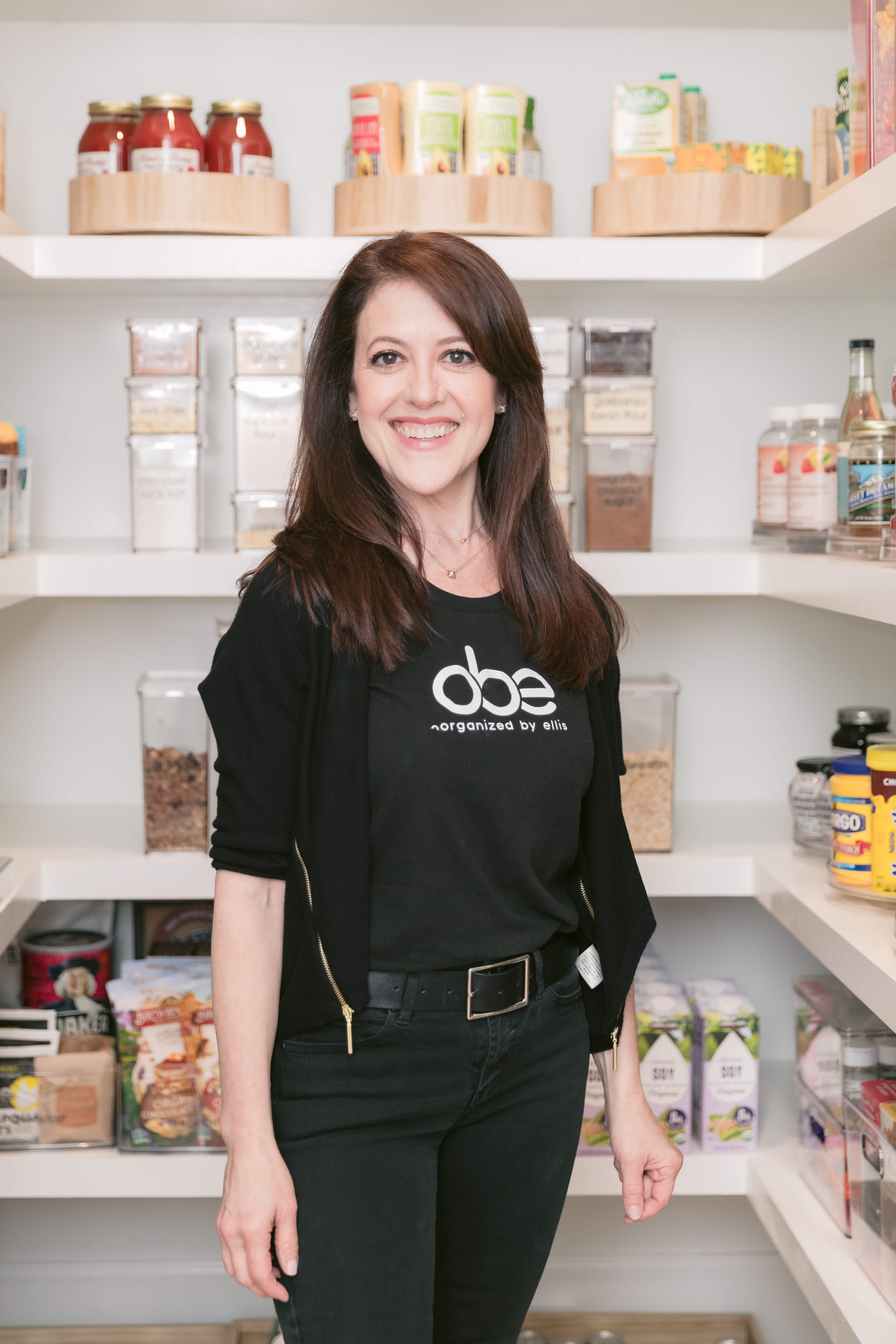 A woman standing in a kitchen with shelves full of gluten-free food.