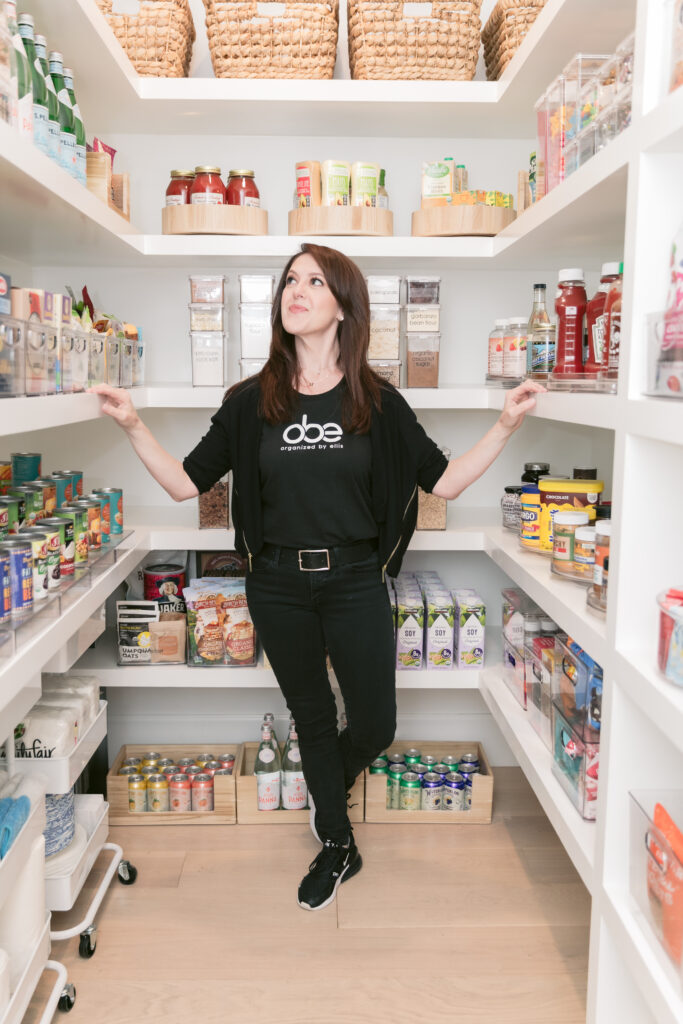 A woman standing in front of a well-stocked pantry full of gluten-free food.
