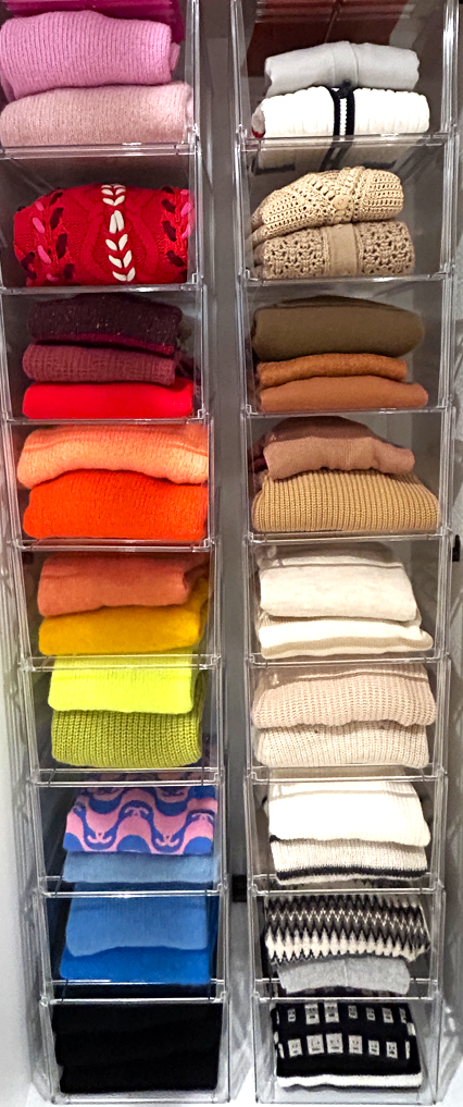 A stack of colorful sweaters in a clear wardrobe storage box.