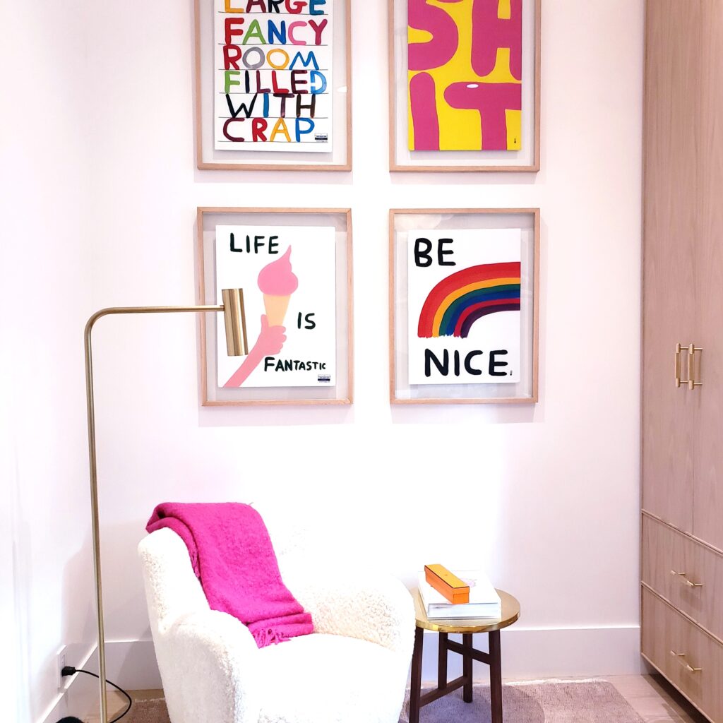A room with a chair and a few colorful framed posters in an office.