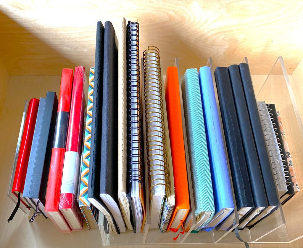 A stack of office notebooks on a shelf.