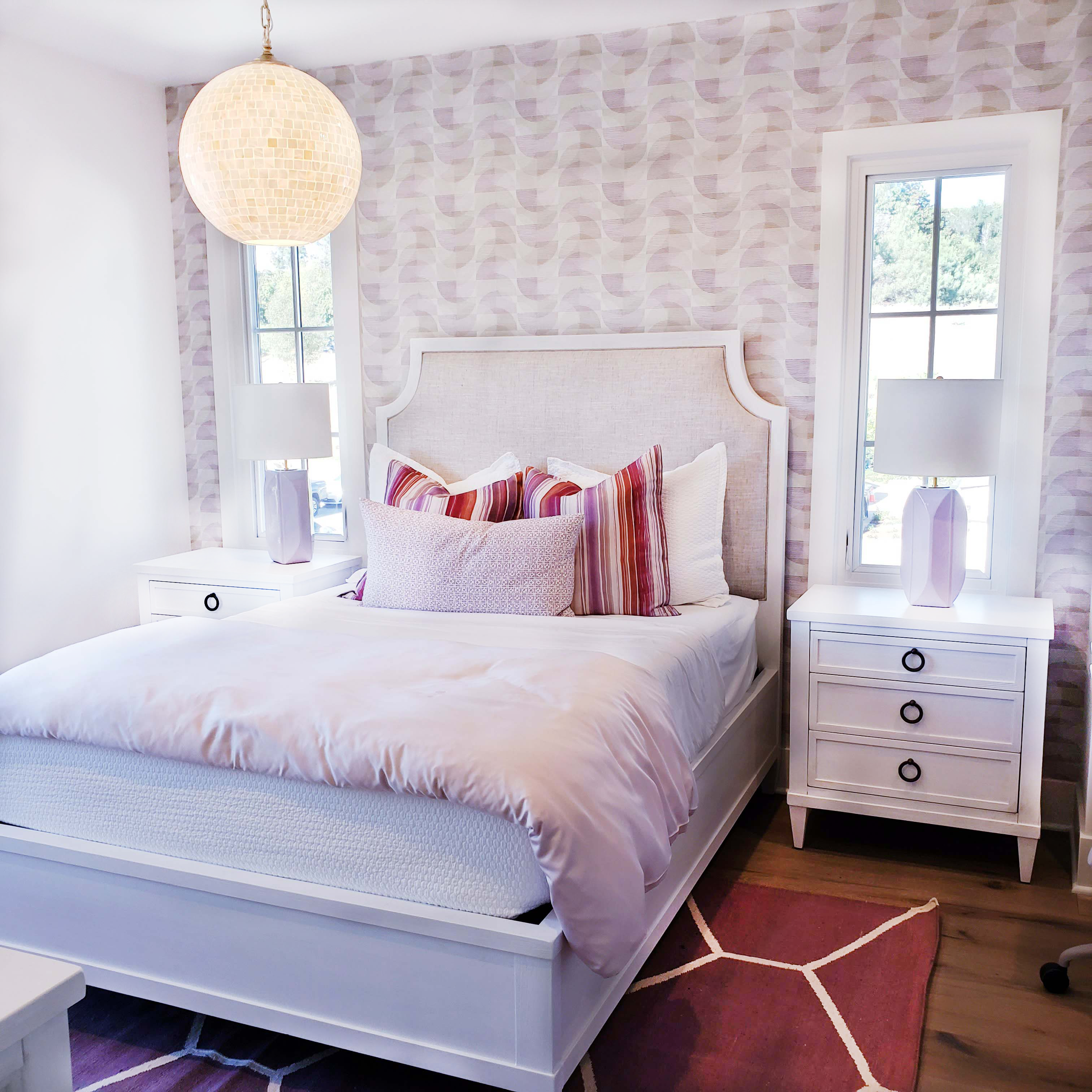 A bedroom, fresh from spring cleaning, with a white bed and pink wallpaper.