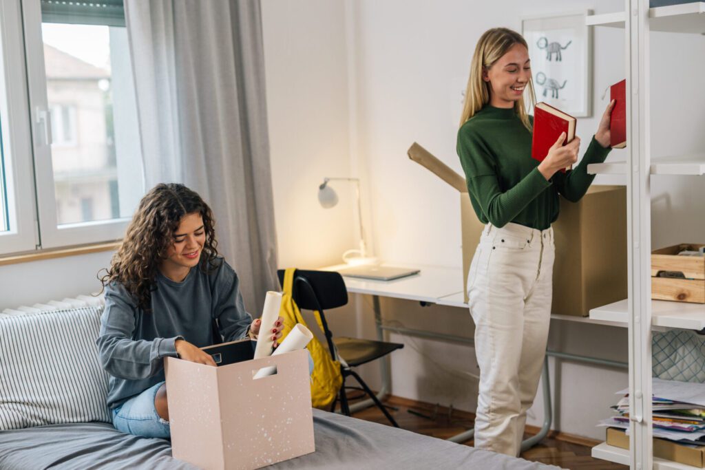 Two women unpacking books in a room.