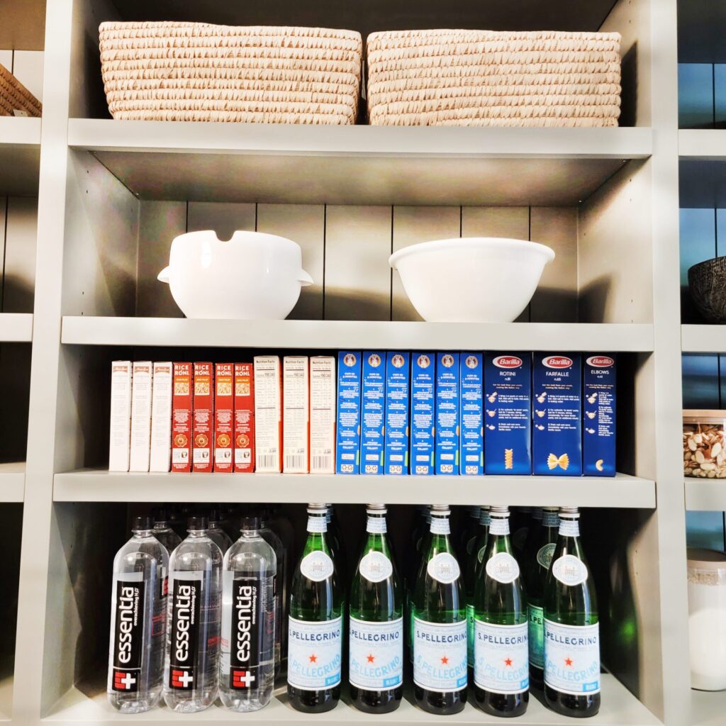 Organized pantry shelves with beverages and pasta.