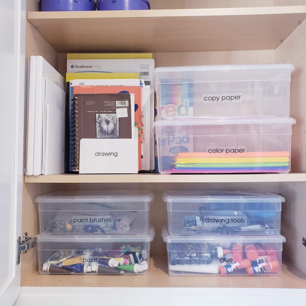 Art supplies organized in labeled storage containers.