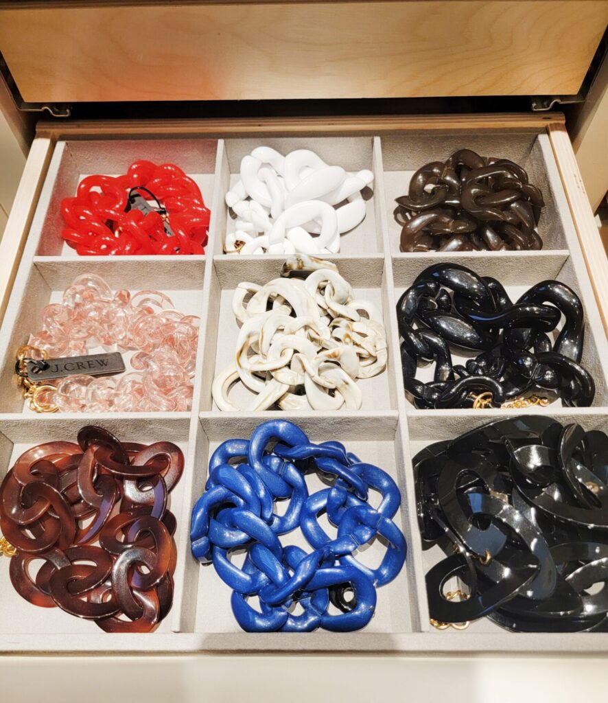 Colorful chain accessories organized in drawer.